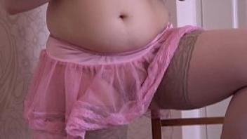 A girl in a pink skirt and in stockings masturbates her pussy